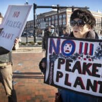 Mary Klug holds up a sign saying "No Peaker Plant" at a rally to stop the construction of a new gas peaker power plant in Peabody. (Robin Lubbock/WBUR)