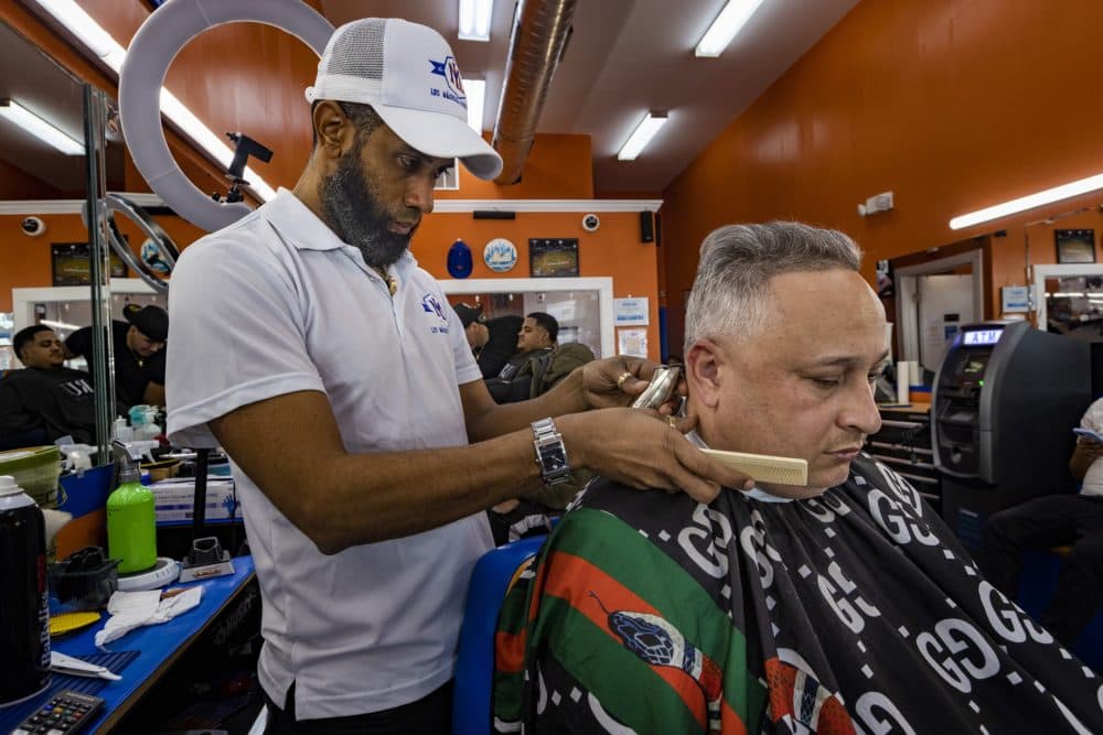 Harlen Lara gives a haircut to a patron at Los Magicos barbershop in Dorchester. (Jesse Costa/WBUR)