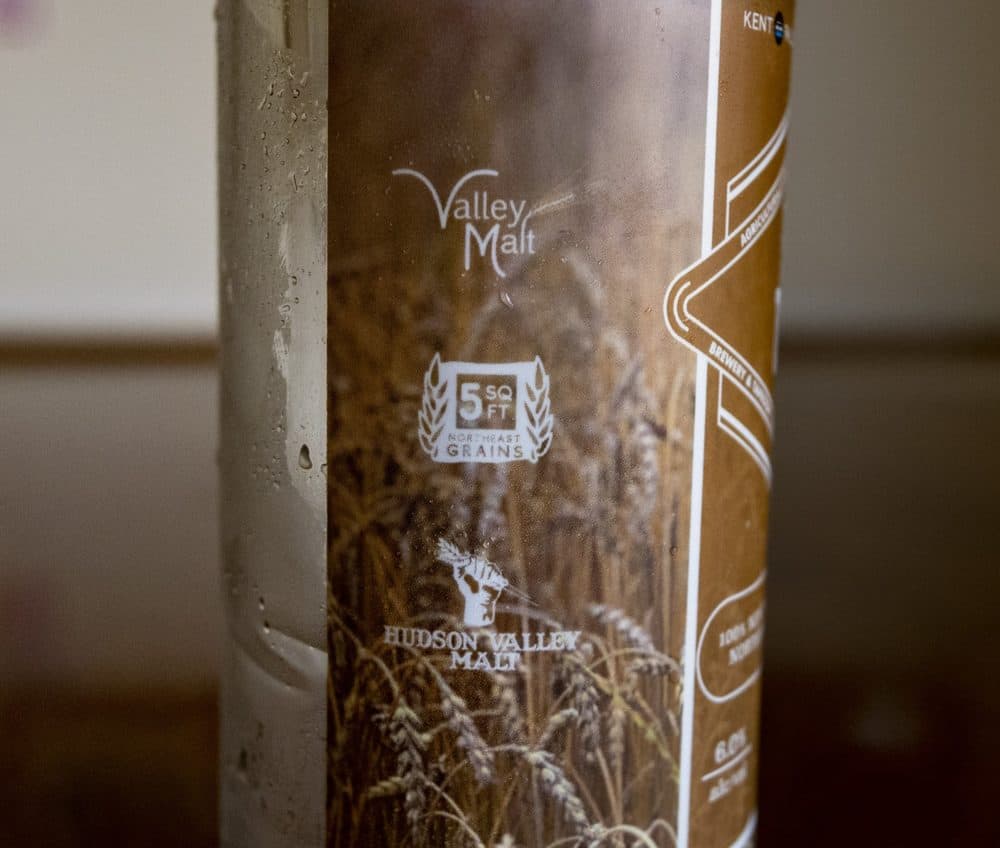 The logo of the Northeast Grainshed Alliance SQFT Project on the can indicates that each 16oz Exhibit ‘A’ Raising the Grain can of beer uses 5 square feet of local farmland. The project’s mission is to bridge the gap in consumer awareness of Northeast grain farmland. (Jesse Costa/WBUR)