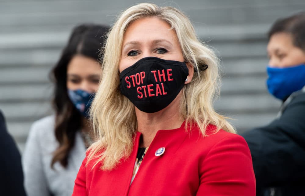 Rep. Marjorie Taylor Greene, Republican of Georgia, holds up a "Stop the Steal" mask while speaking with fellow first-term Republican members of Congress on the steps of the US Capitol in Washington, DC, Jan. 4, 2021. (Saul Loeb/AFP via Getty Images)