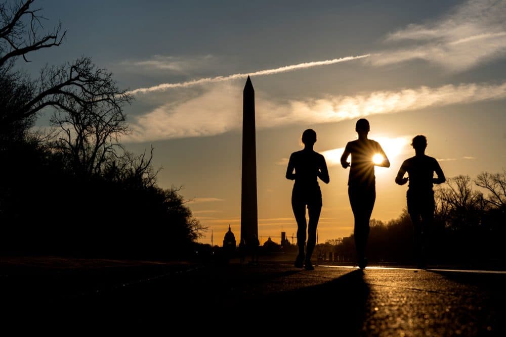 People run along the National Mall at sunrise in Washington, DC, on March 15, 2022. (Stefani Reynolds/AFP via Getty Images)