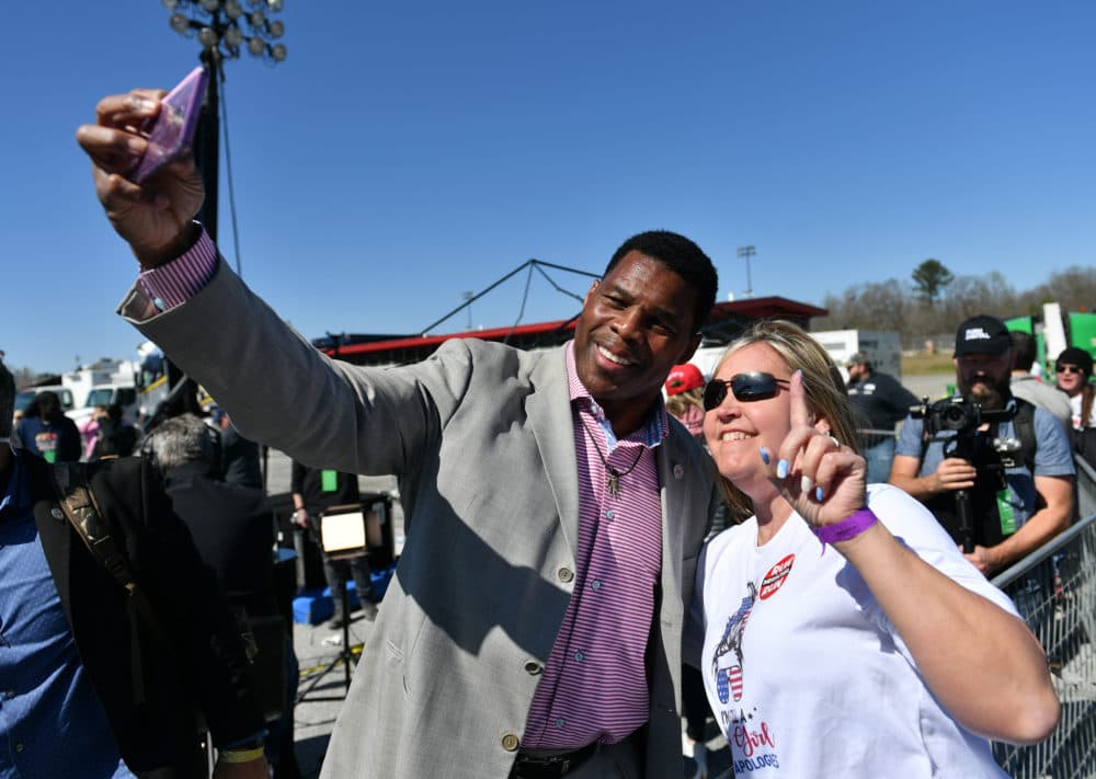 Republican Senate candidate Herschel Walker and a woman take a selfie during former US President Donald J Trump's "Save America" rally with David Perdue, Burt Jones, Marjorie Taylor Greene and Vernon Jones in Commerce, GA, on March, 26, 2022. (Peter Zay/Anadolu Agency via Getty Images)