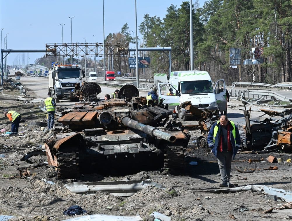 Road service workers clean debris around a burnt Russian tank and vehicle on a road west of Kyiv, on April 7, 2022, during Russia's military invasion launched on Ukraine. Six weeks after Russia invaded its neighbor, its troops have withdrawn from Kyiv and Ukraine's north and are focusing on the country's southeast, where desperate attempts are under way to evacuate civilians. (Genya Savilov/AFP via Getty Images)