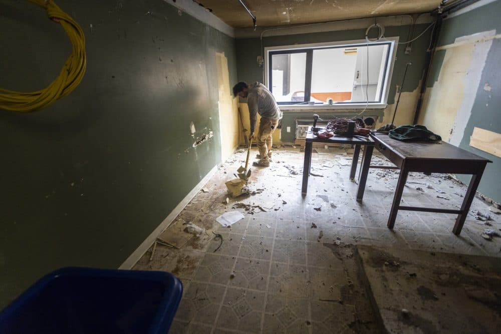 A contractor removes flooring during the conversion of the former Rodeway Inn in Brockton to 69 units of permanent supportive housing. (Jesse Costa/WBUR)