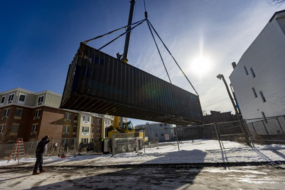 The shipping container holding the greenhouse is lifted onto the property at Eastie Farm last February. (Jesse Costa/WBUR)