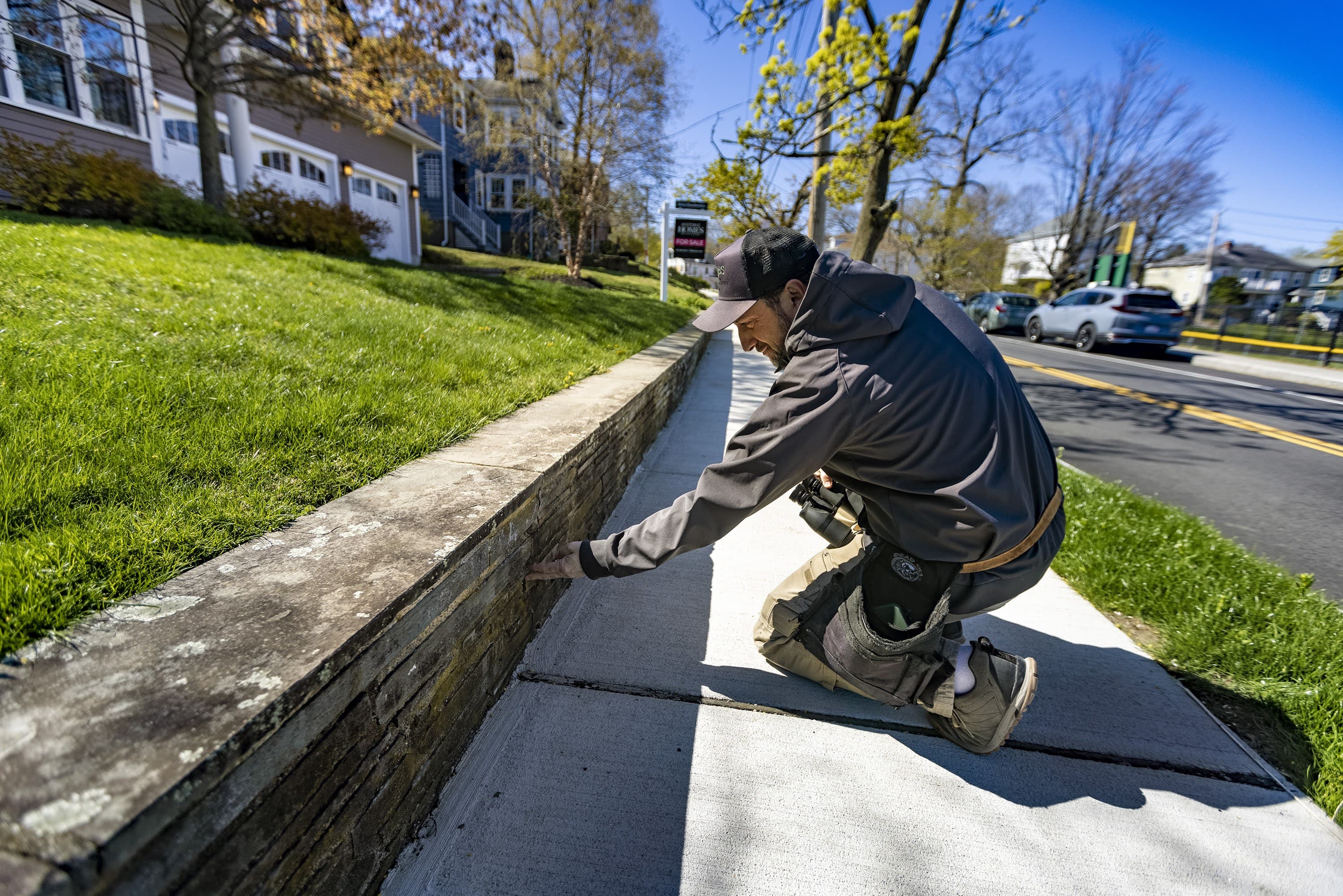 Alex Steinberg, of JBS Home Inspections, examines the condition of a stone wall in front of a house during an inspection in Newton. (Jesse Costa/WBUR)