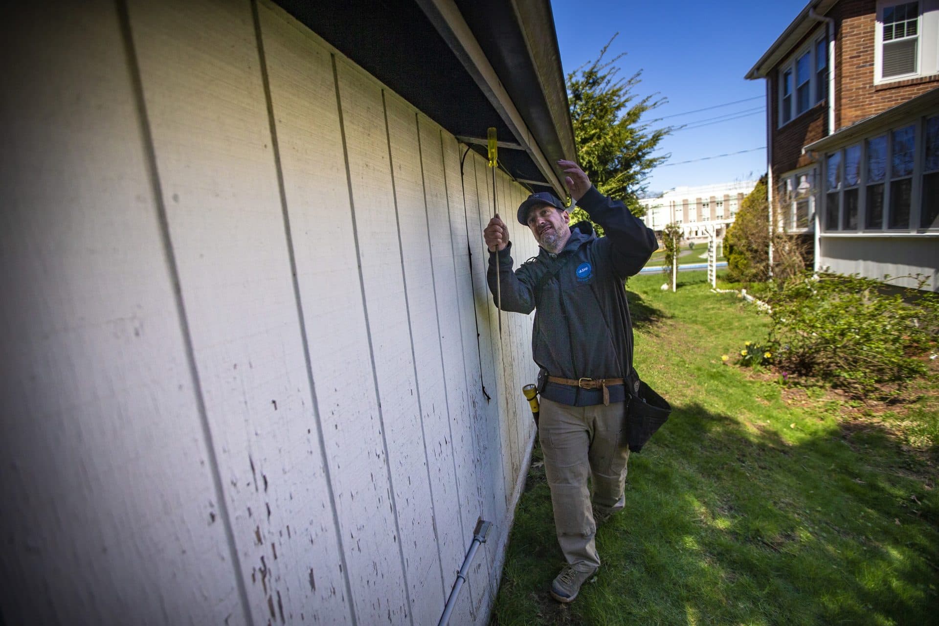Alex Steinberg of JBS Home Inspections tests the bottom of gutters during a home inspection in Newton.  (Jesse Costa/WBUR)