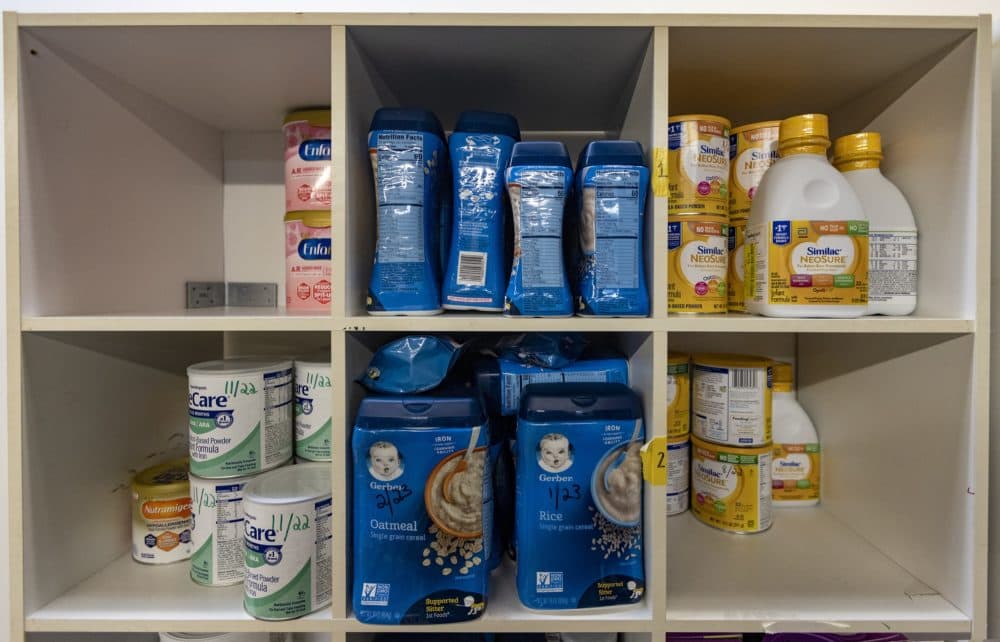 Containers of baby formula and cereal on shelves at the Neighbors in Need Diaper Bank in Lawrence. (Jesse Costa/WBUR)