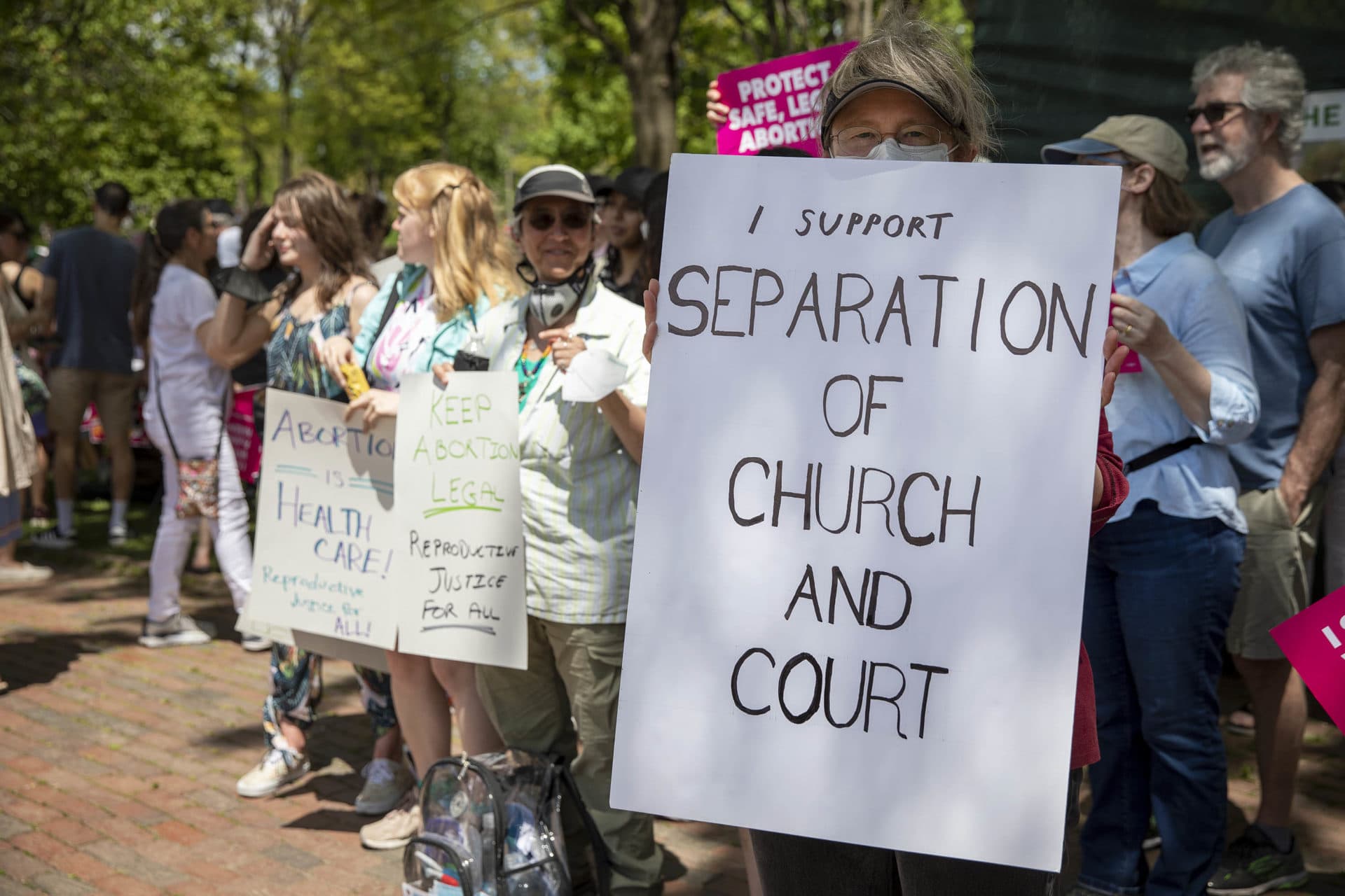 Protester Willa Michener holds up a sign saying "I Support Separation Of Church And Court" at the Bans Off Our Bodies rally on Boston Common. (Robin Lubbock/WBUR)
