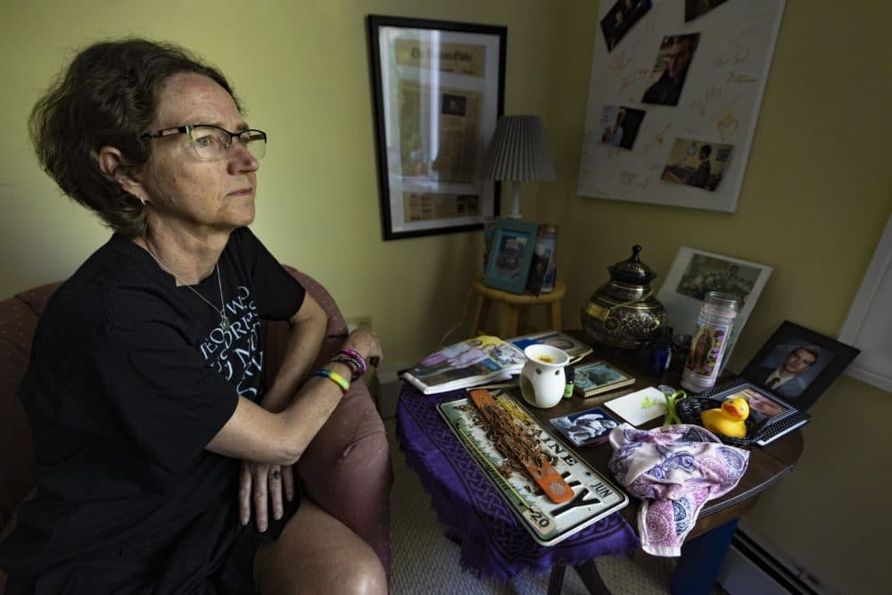 Catherine Nash sits at the memorial she created for her son, Jesse Harvey, who ran a grassroots needle distribution program in Maine. He died of an overdose in 2020. (Jesse Costa/WBUR)