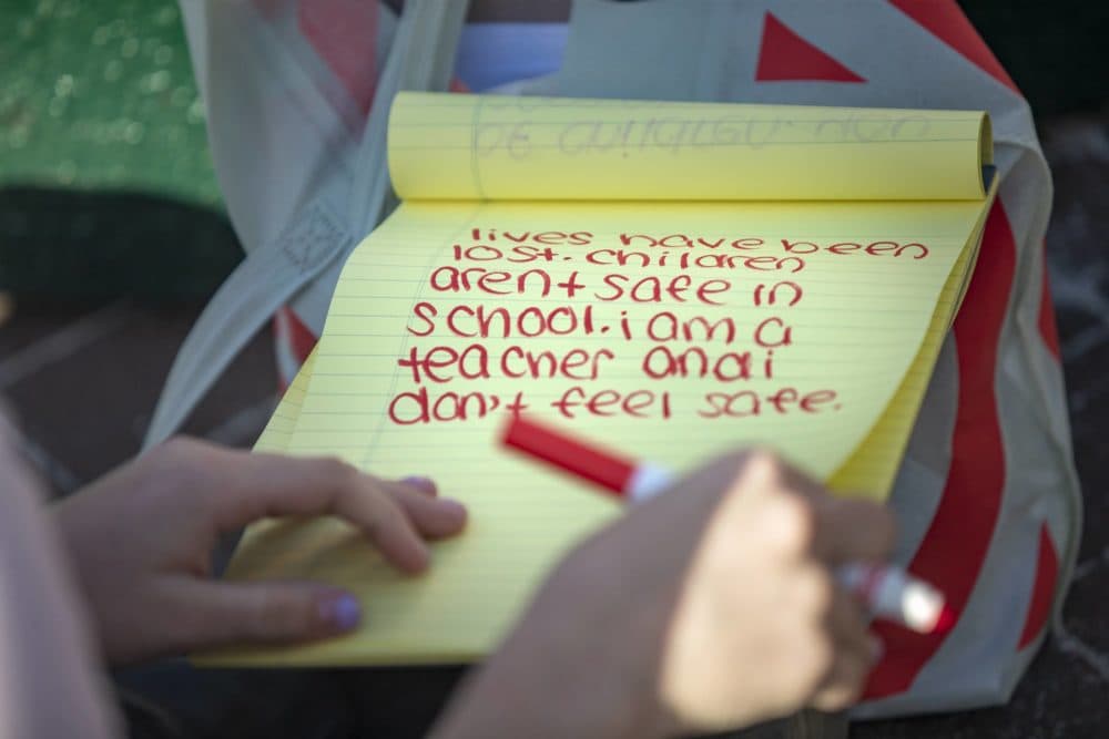 Teacher Kathleen Giffels writes down her thoughts onto a legal pad during the memorial service in Copley Square remembering the victims of the school shooting at Robb Elementary School in Uvalde, Texas. (Jesse Costa/WBUR)