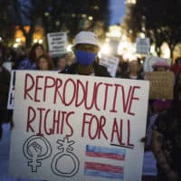 Tripp Hopkins, center, attends a rally to protest the news that the U.S. Supreme Court could be poised to overturn the landmark Roe v. Wade case that legalized abortion nationwide, Tuesday, May 3, 2022, at the Statehouse in Providence, R.I. (David Goldman/AP)