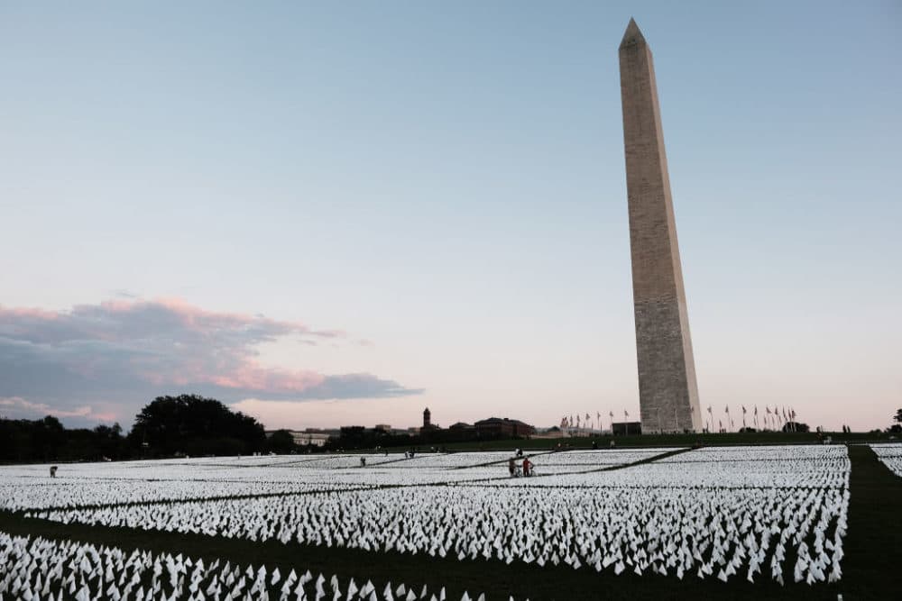 Visitors walk through 'In America: Remember,' a public art installation commemorating all the Americans who have died due to COVID-19 near the Washington Monument on September 18, 2021 in Washington, DC. The concept of artist Suzanne Brennan Firstenberg, the installation includes more than 660,000 small plastic flags, some with personal messages to those who have died, planted in 20 acres of the National Mall. (Spencer Platt/Getty Images)