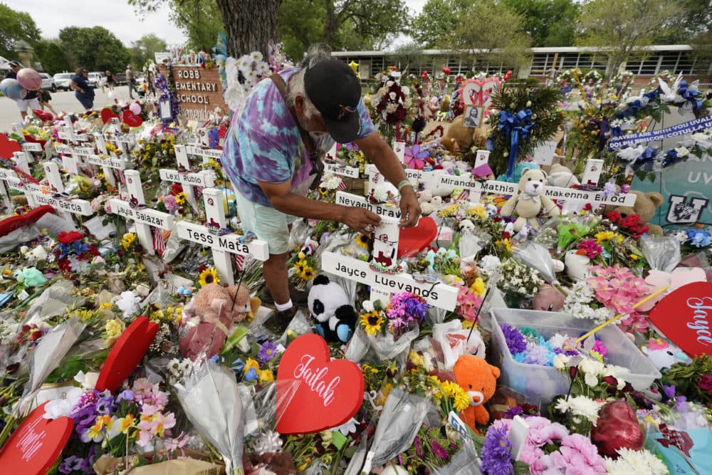 A visitor places bracelets on crosses at a memorial as he and others pay their respects to the victims killed in last week's Robb Elementary School shooting, Tuesday, May 31, 2022, in Uvalde, Texas. (Eric Gay/AP)