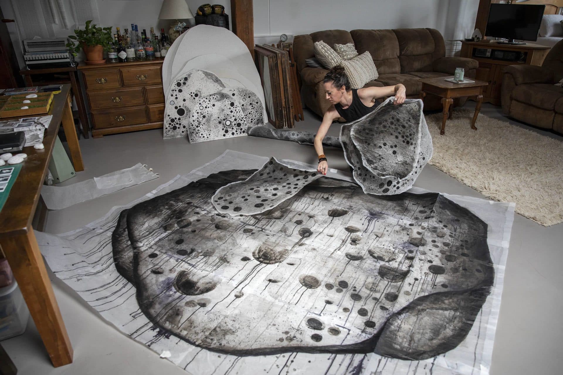 Kristen Mallia looks through her work made with India ink on tracing paper. (Robin Lubbock/WBUR)