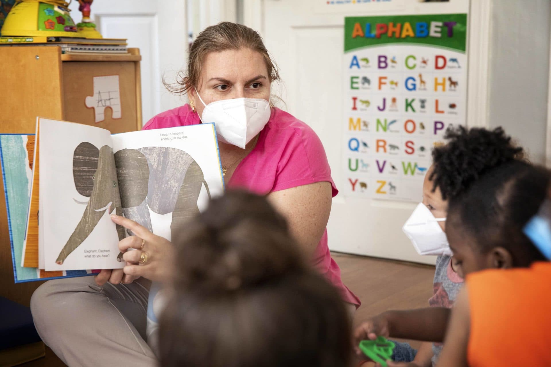 Llanet Montoya, who runs an in-home child care in Worcester, reads a book to a group of children. (Robin Lubbock/WBUR)