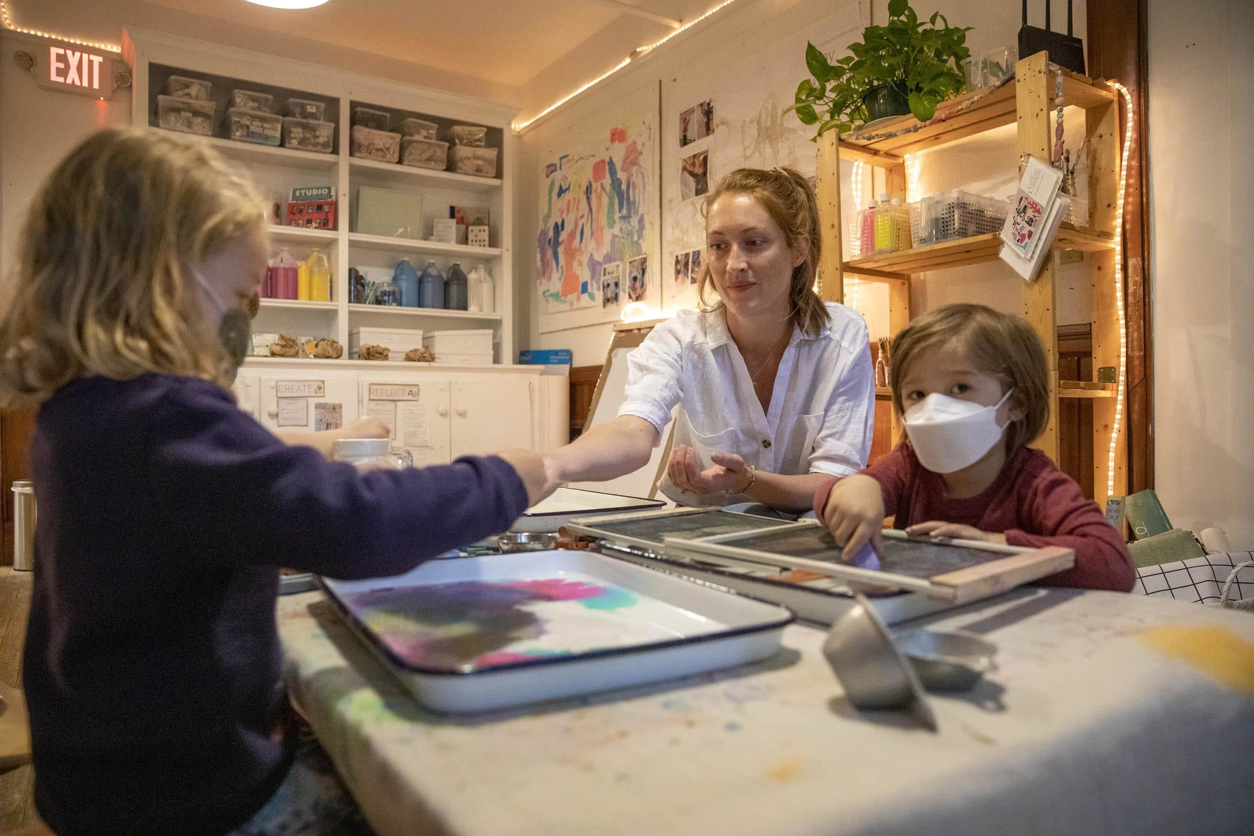 Art teacher Amanda McCracken works on a painting project with students in the art studio at the Newtowne School in Cambridge. (Robin Lubbock/WBUR)