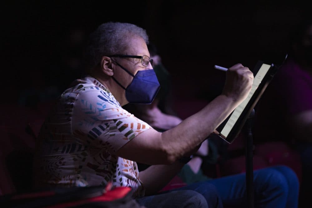 Composer Anthony Davis makes notes as he watches the cast and orchestra perform during a rehearsal of “X: The Life and Times of Malcolm X” at the Strand Theatre. (Jesse Costa/WBUR)