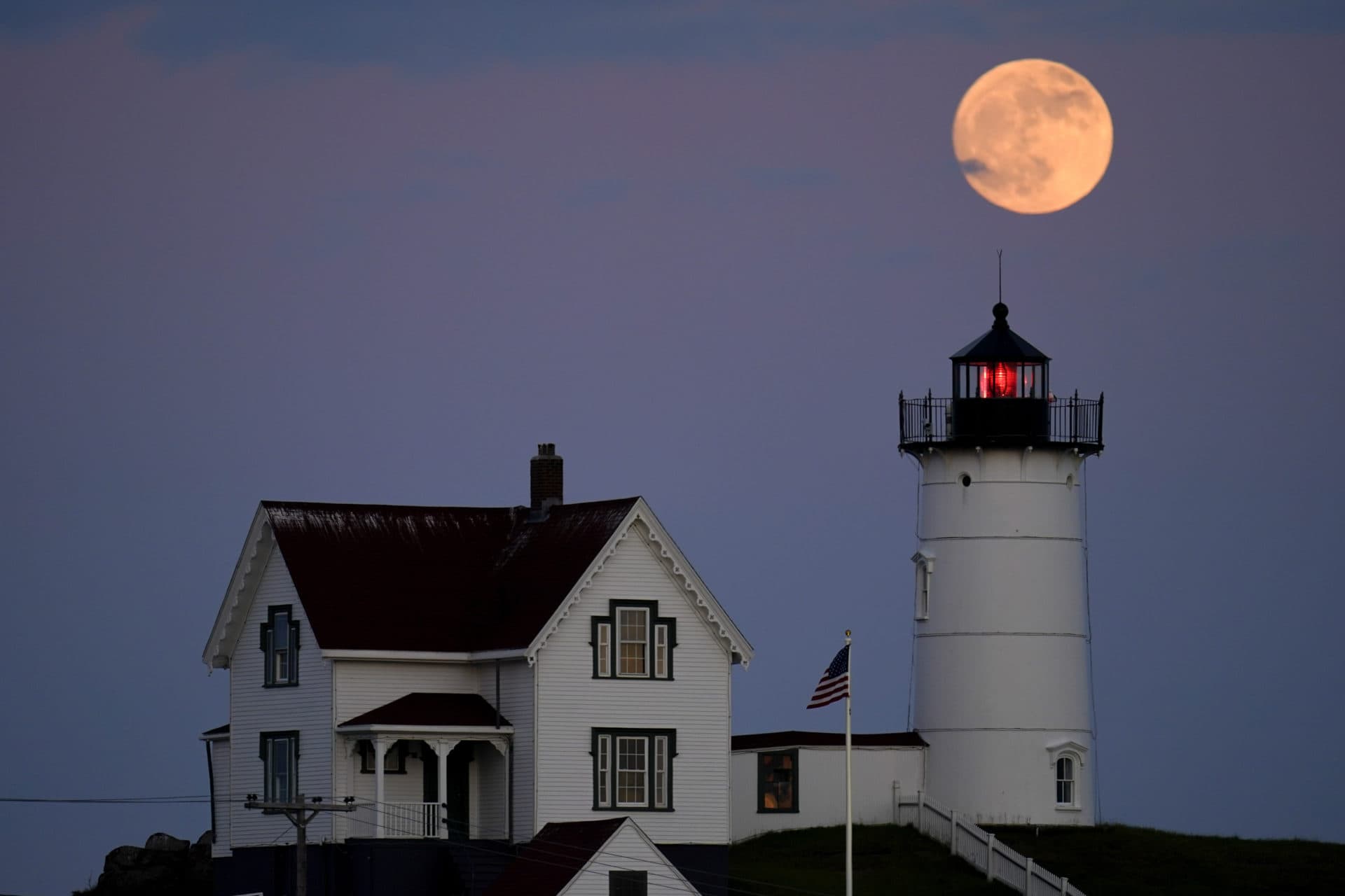 Une lune gibbeuse croissante est vue à 98% pour cent alors qu'elle se lève près du Nubble Light, le lundi 13 juin 2022, à York, dans le Maine.  (Julio Cortez/AP)