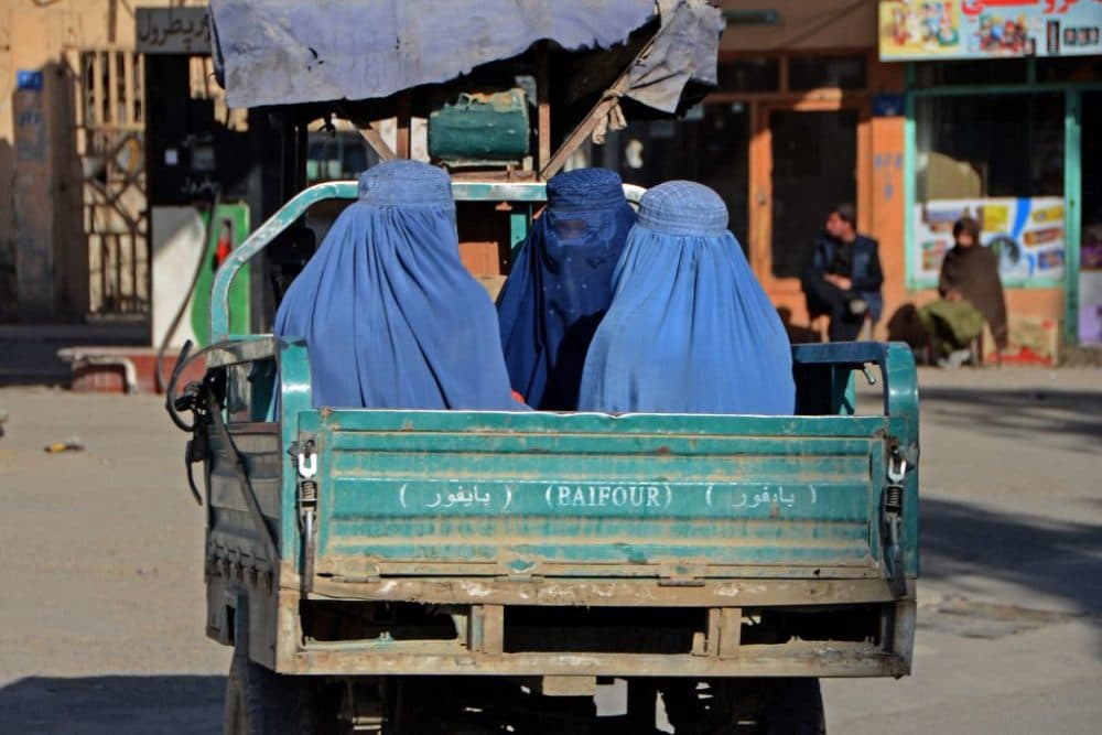 Burqa-clad women travel in a vehicle along a street in Kandahar on December 18, 2021. (Photo by Javed Tanveer/AFP via Getty Images)